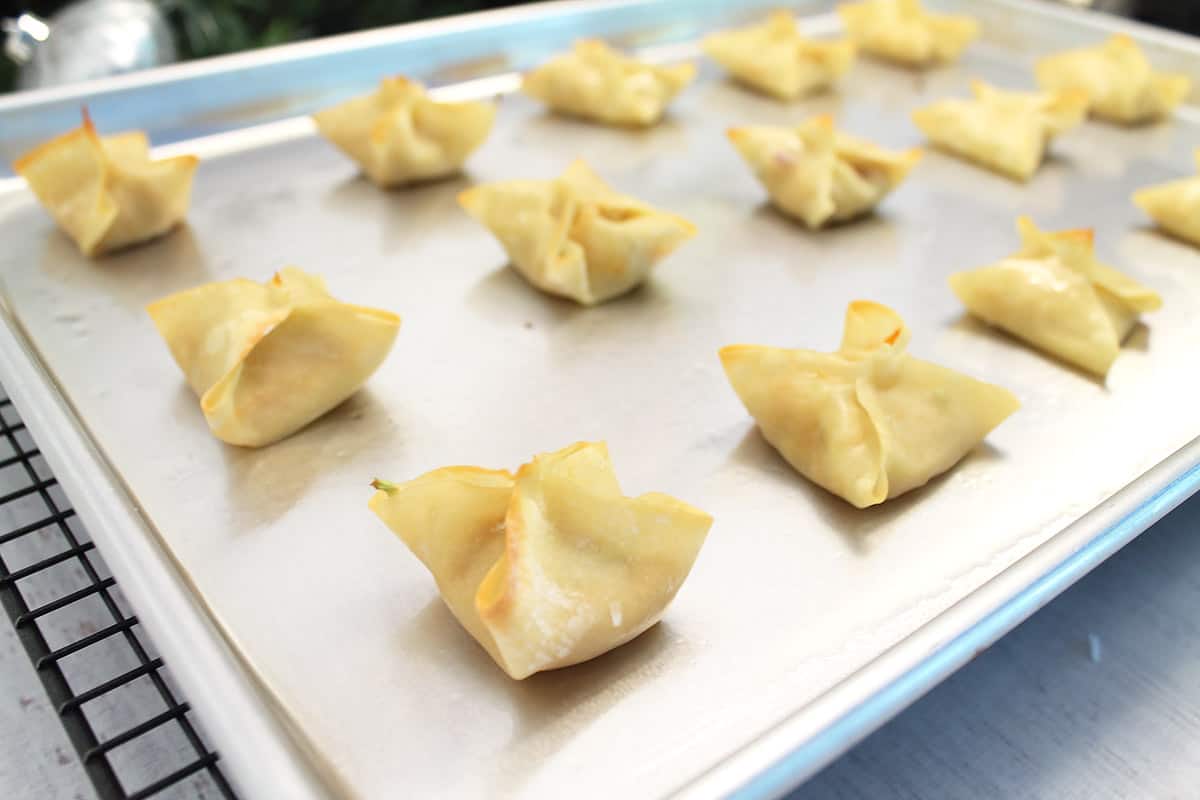 Baking sheet full of baked chicken wontons.
