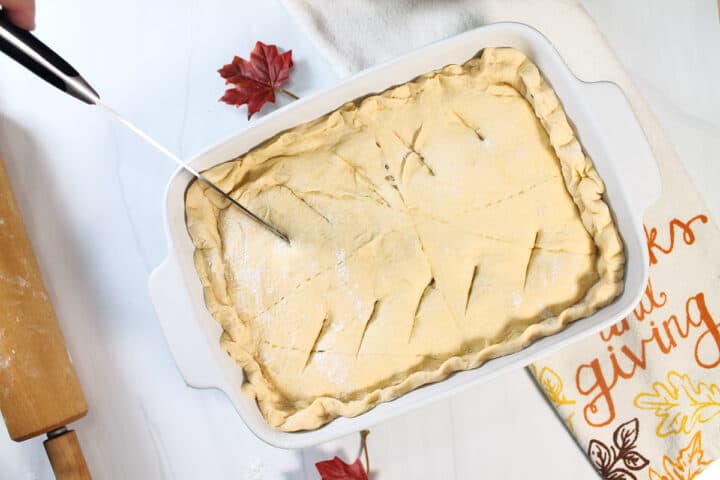 Crescent dough on top of casserole, cutting slits in top.