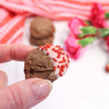 Holding white chocolate dipped meringue cookie.