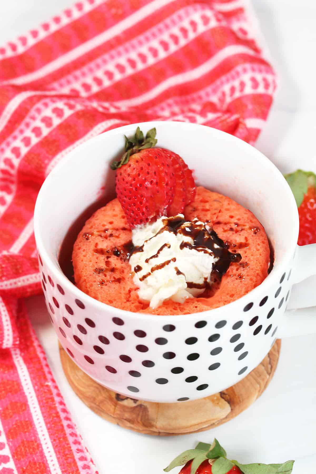 Strawberry Mug Cake with whipped cream and ganache in mug.