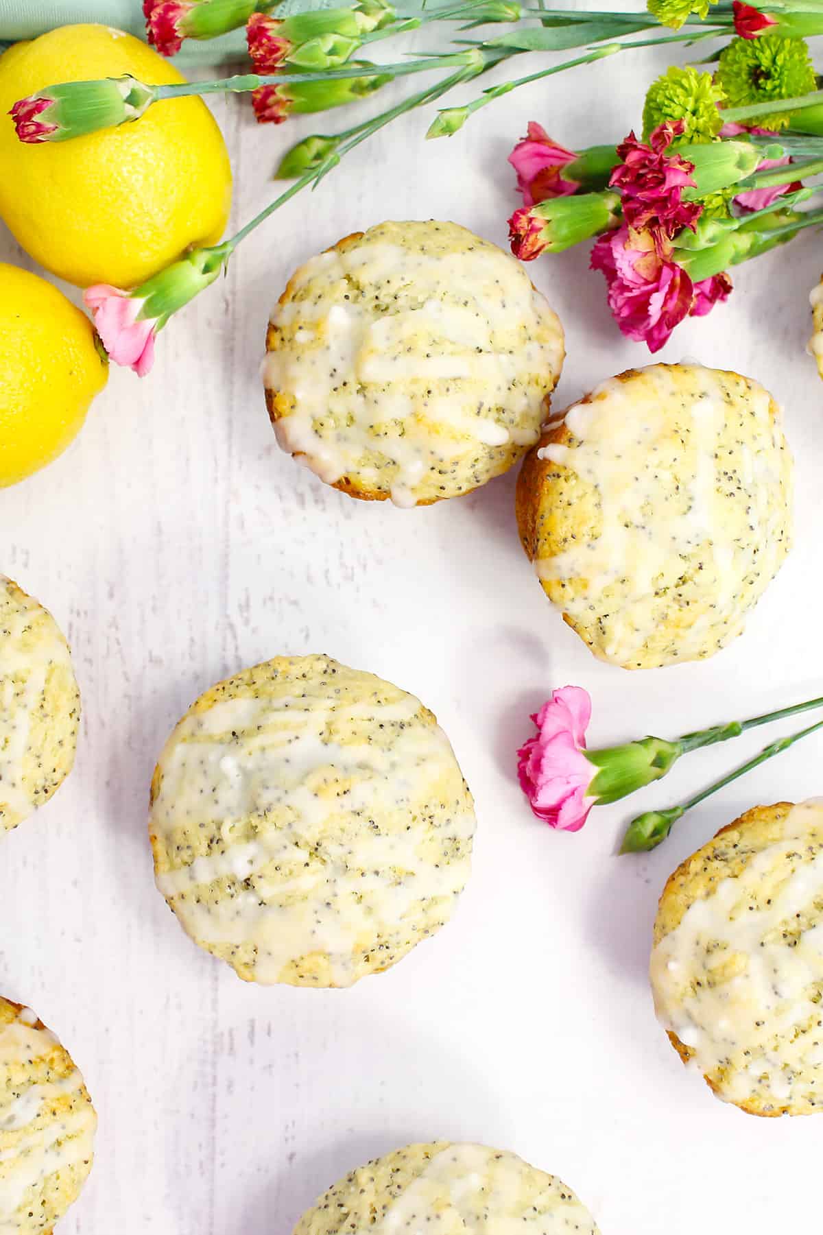 Scattered muffins on table with flowers.