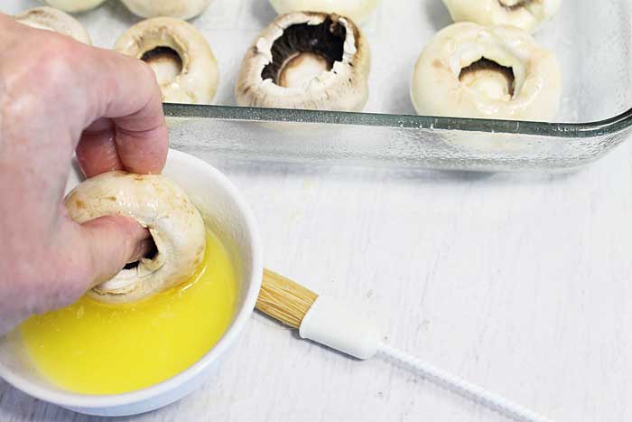 Spinach Stuffed Mushrooms dipping in butter | 2 Cookin Mamas