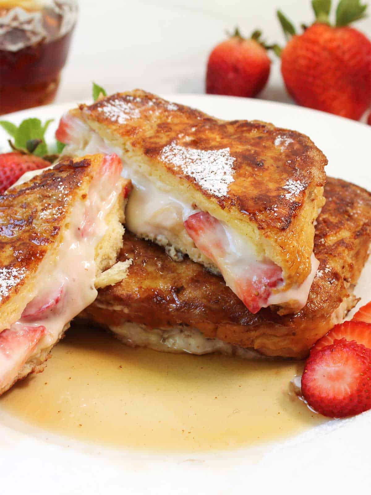 Halved strawberry French toast on serving plate.