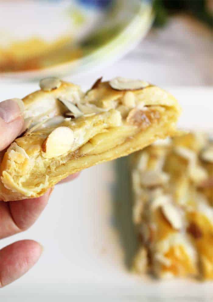 Holding slice of pastry to show filling.