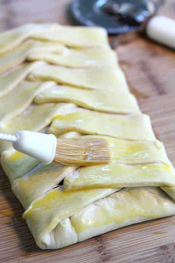 Brushing uncooked pastry with egg wash.
