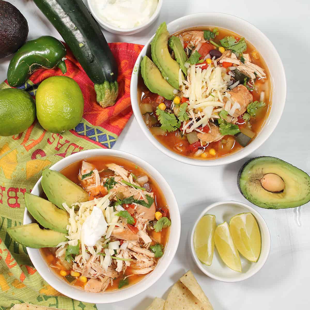 Overhead of two bowls of crockpot chicken tortilla soup.
