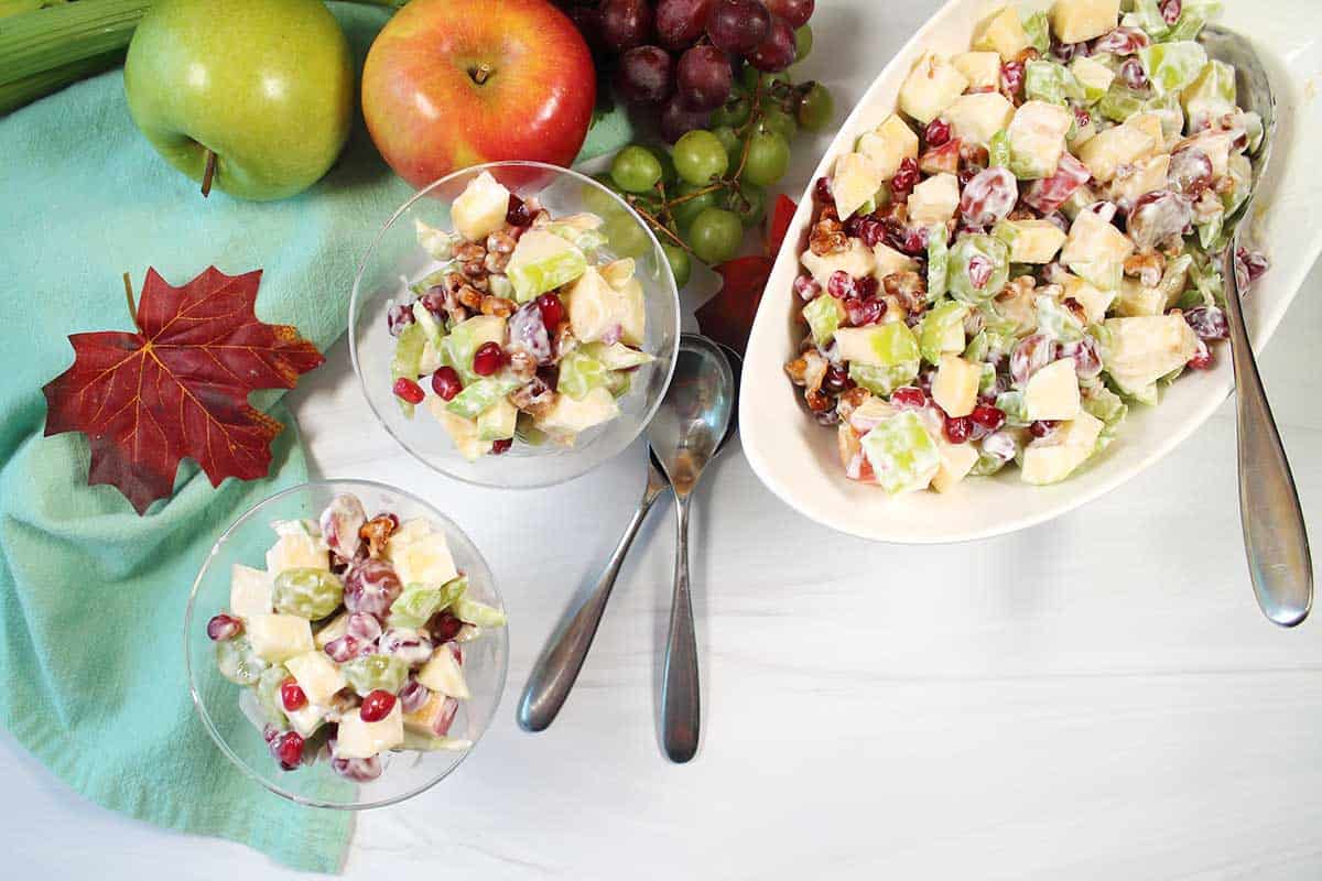 Two servings of apple walnut salad with serving bowl.