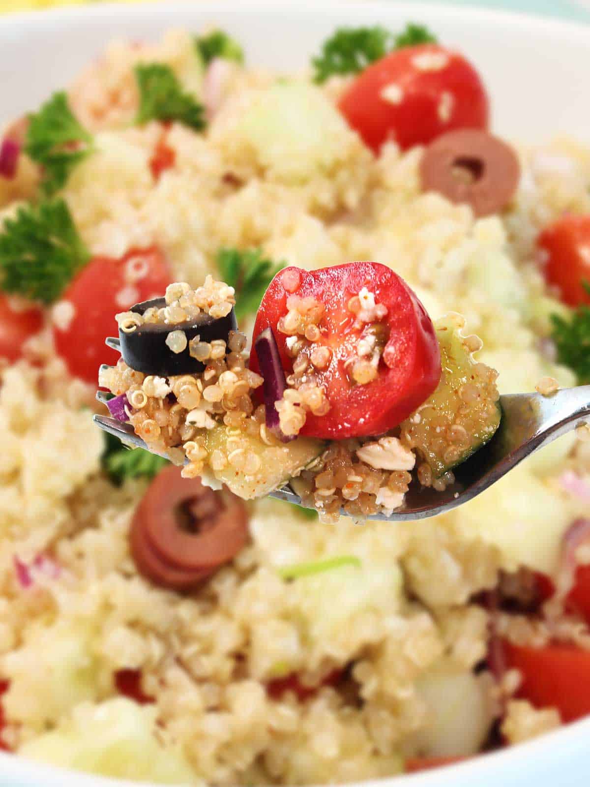 Closeup of bite of Mediterranean quinoa bowl on fork.