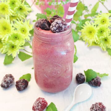 Mason jar filled with blackberry smoothie and garnished with blackberries and mint.