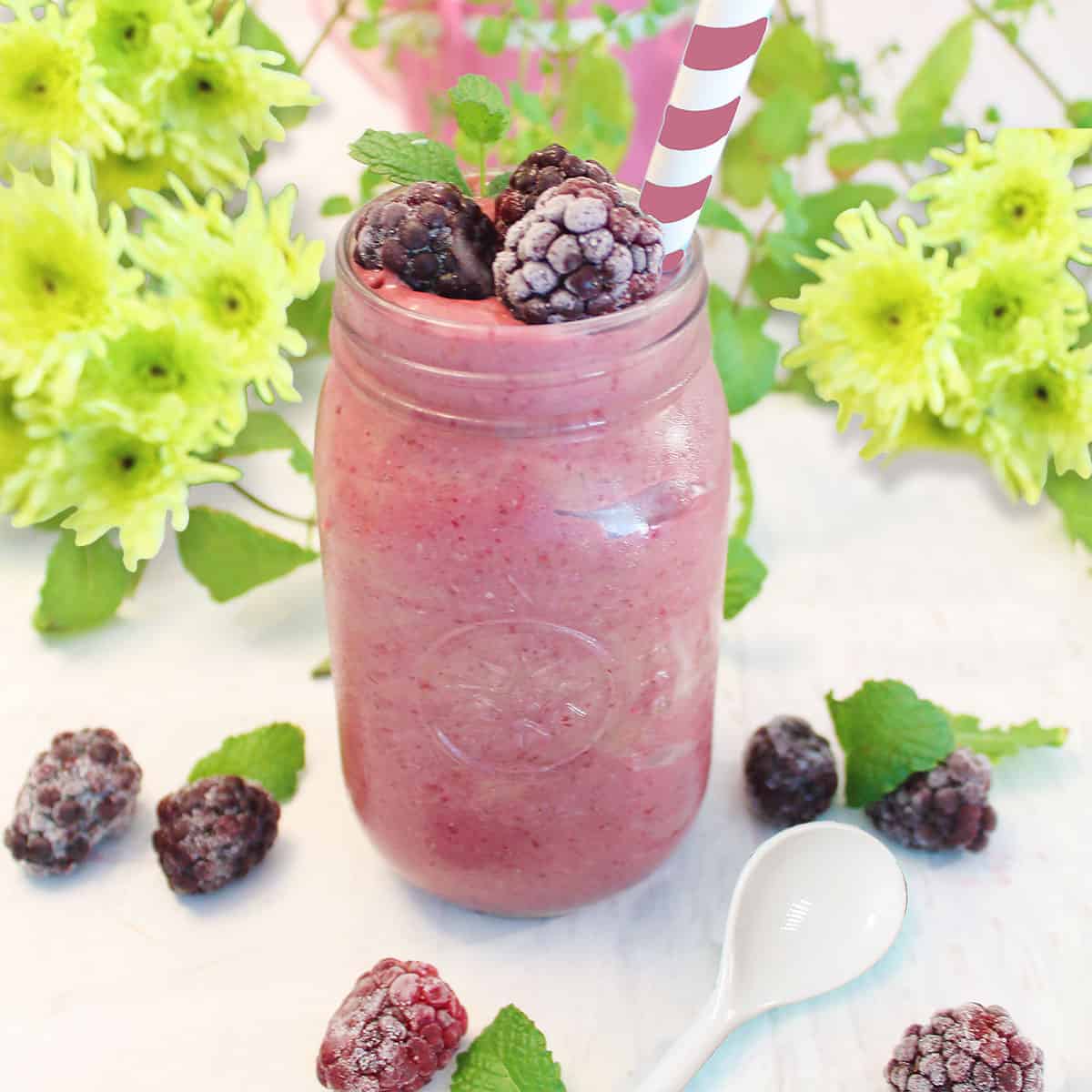 Mason jar filled with blackberry smoothie and garnished with blackberries and mint.
