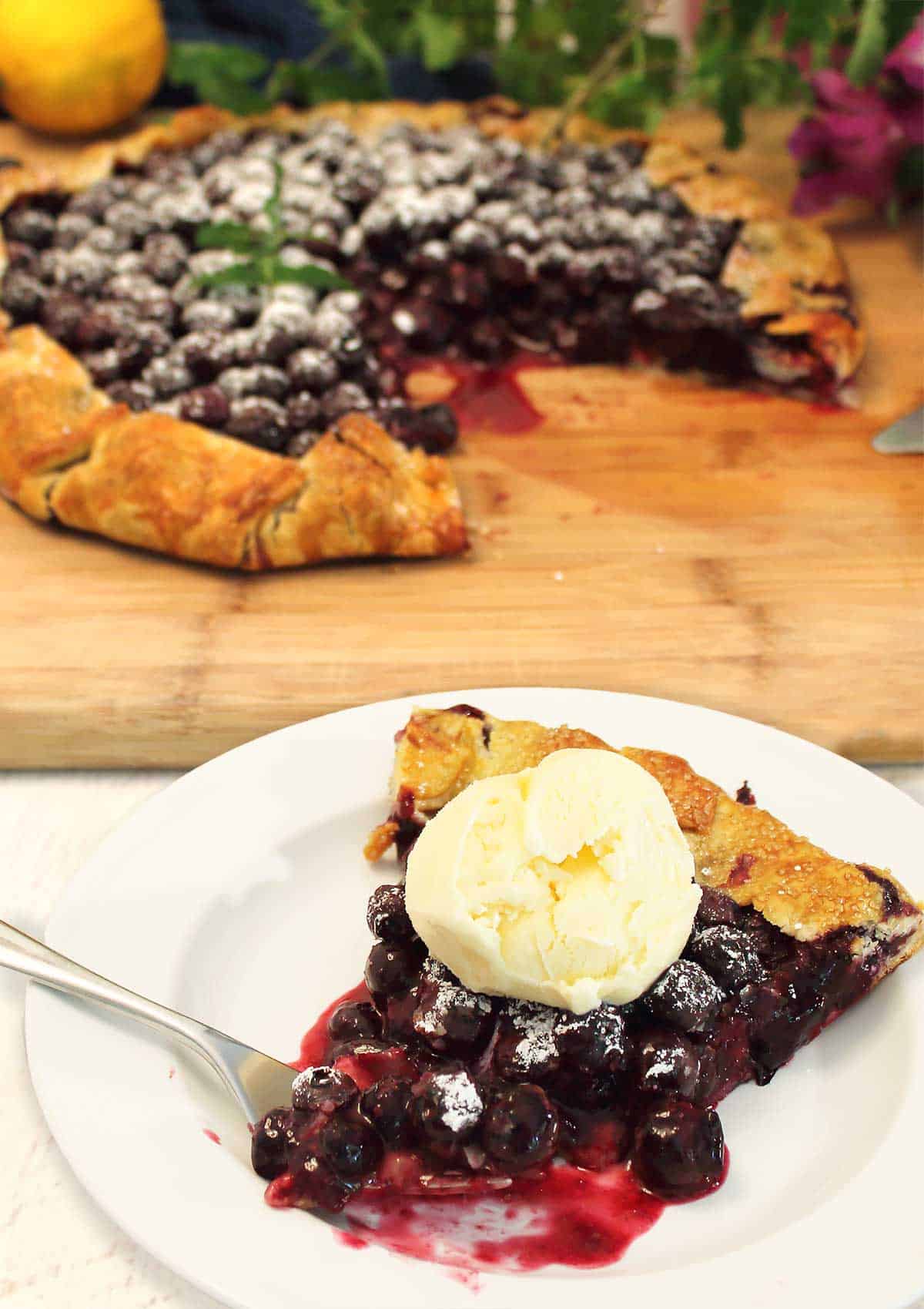 Slice of galette on plate topped with vanilla ice cream.