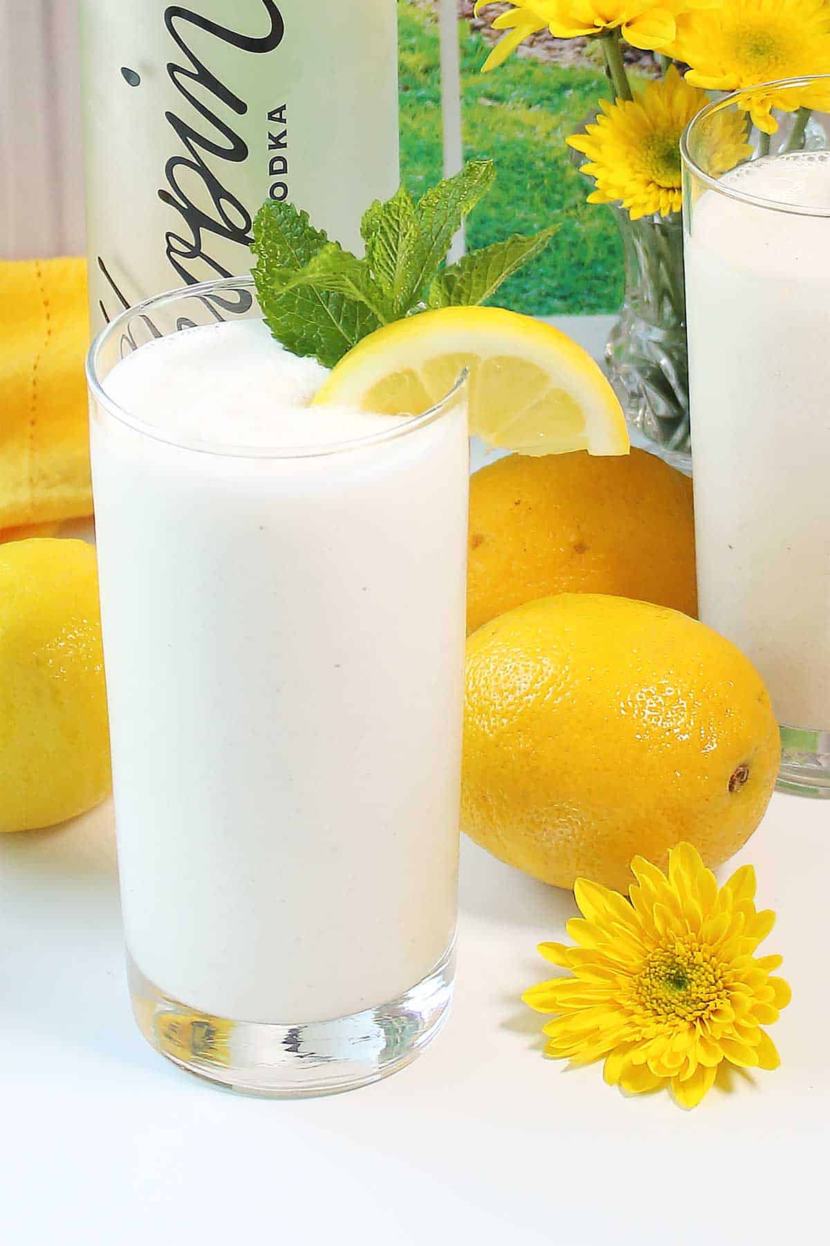 Closeup of frosted lemonade in glass among lemons.