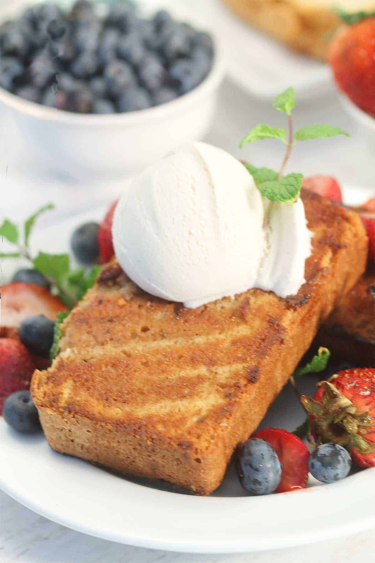 Grilled Cinnamon Sugar Sour Cream Pound Cake | 2 Cookin Mamas Deliciously rich Cinnamon Sugar Sour Cream Pound Cake is a decadent dessert for any occasion. Grill it and top it with ice cream for the perfect addition to your next cookout. #poundcake #cake #dessert #sourcream #cinnamonsugar #grilled #recipe Grilled Pound Cake with ice cream and berries on top.