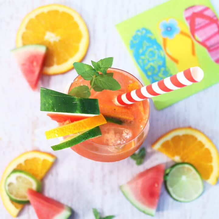 Overhead of single watermelon drink with fruit slices around it.