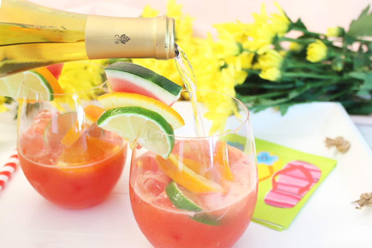 Pouring a little bubbly into glasses with fruit-wine mixture.