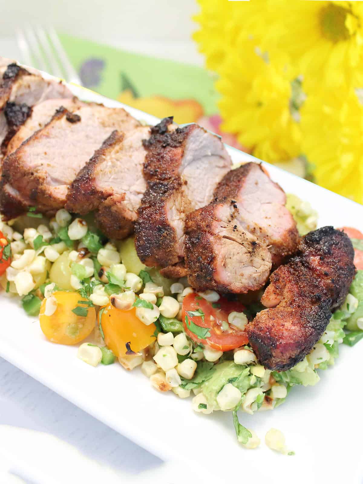 Grilled Tex-Mex Pork Tenderloin on platter over corn salsa.