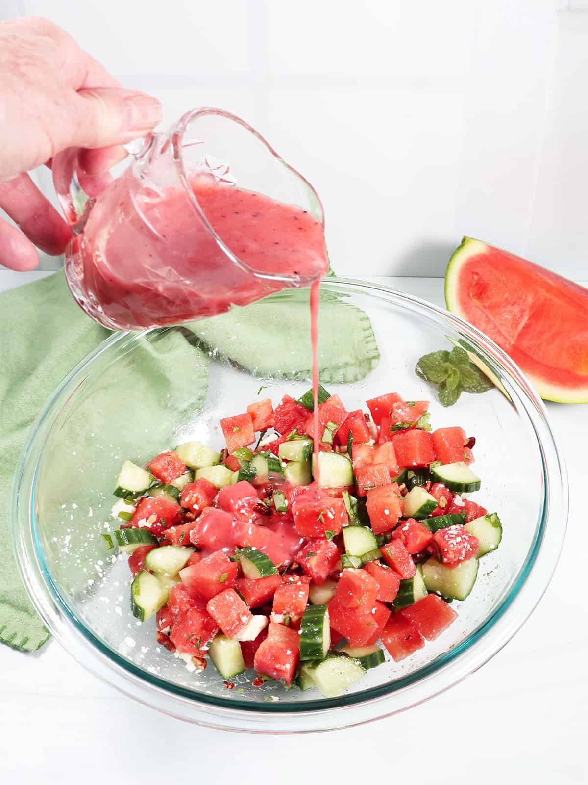 Pouring raspberry vinaigrette over Watermelon Mint Cucumber Salad.
