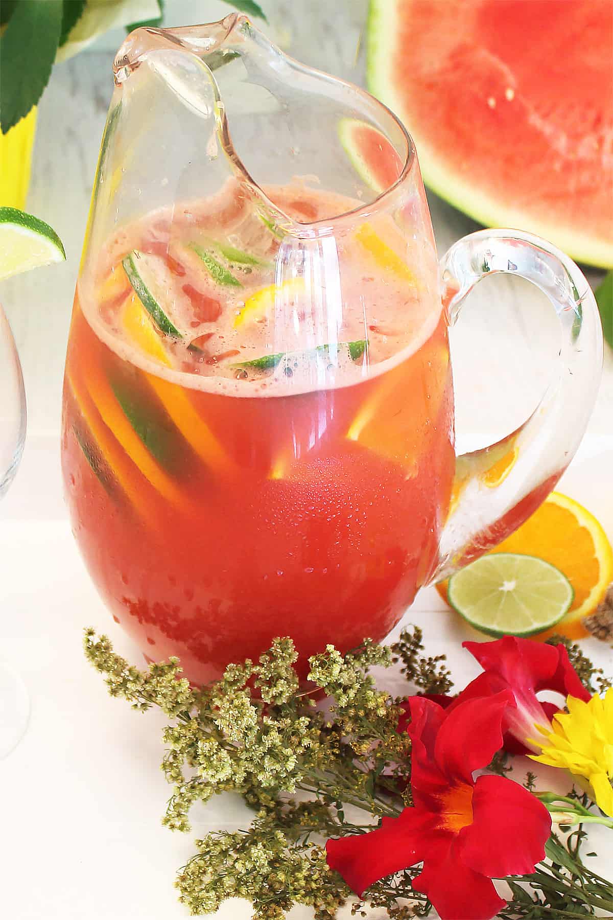 Pitcher of sangria on white tray with flowers in front.