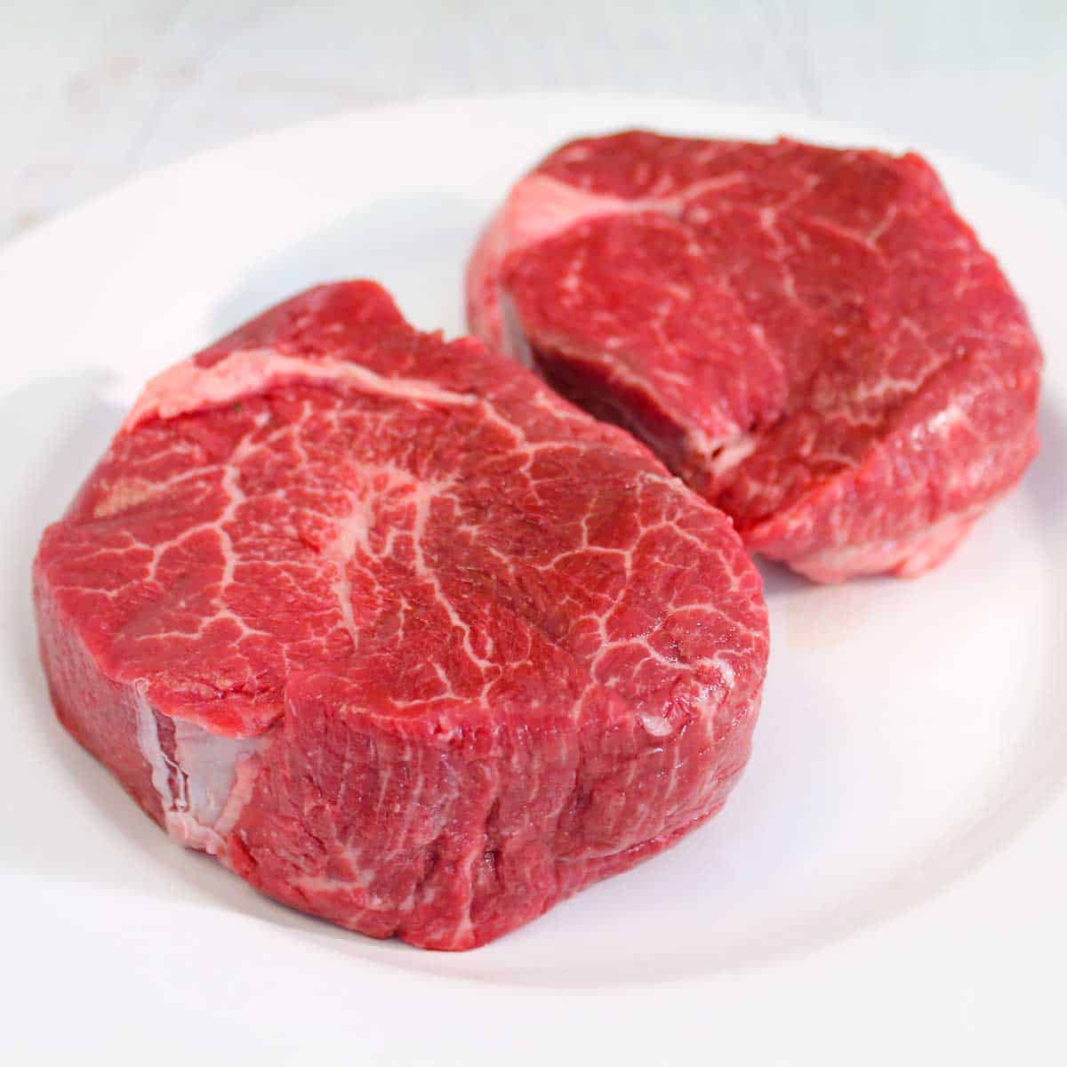 Raw filet mignon steaks on a plate.