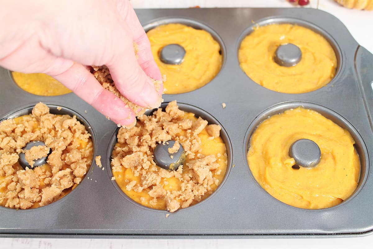 Sprinkling crumb topping on donut batter.