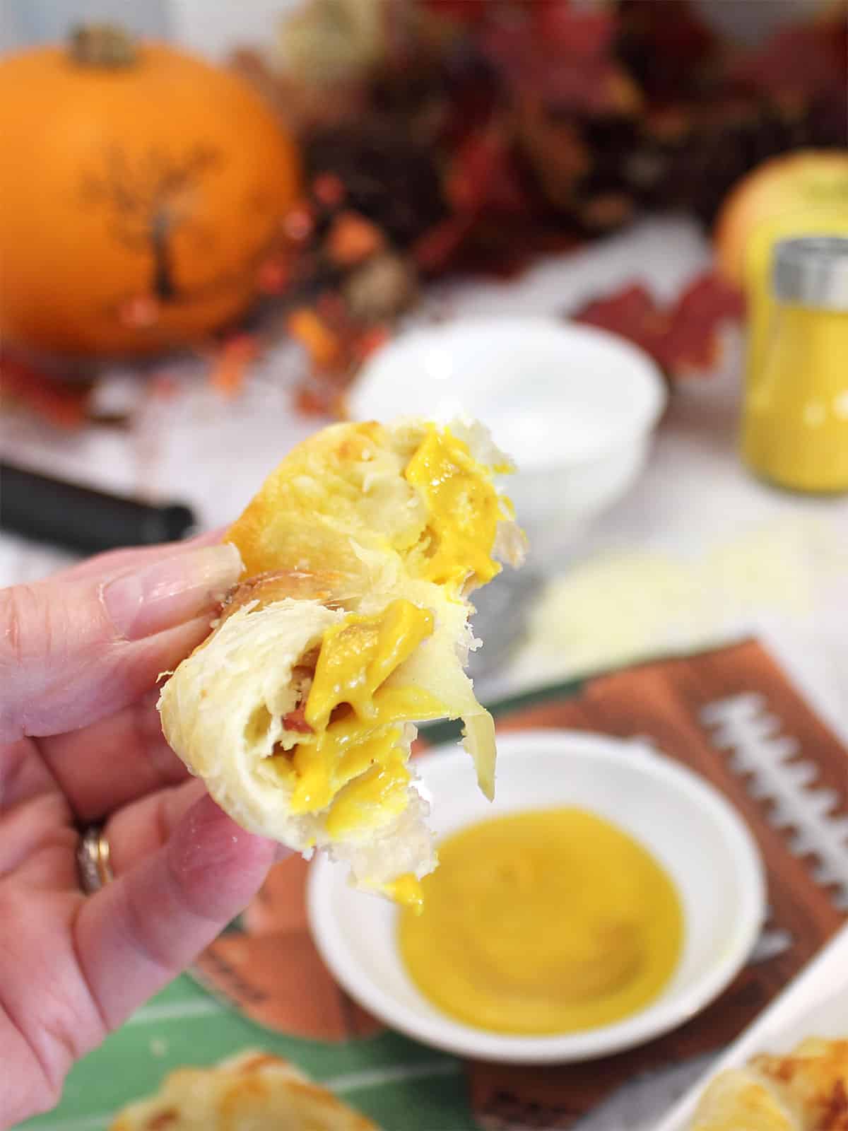 Apple bacon bundle dipped in mustard with bite out.