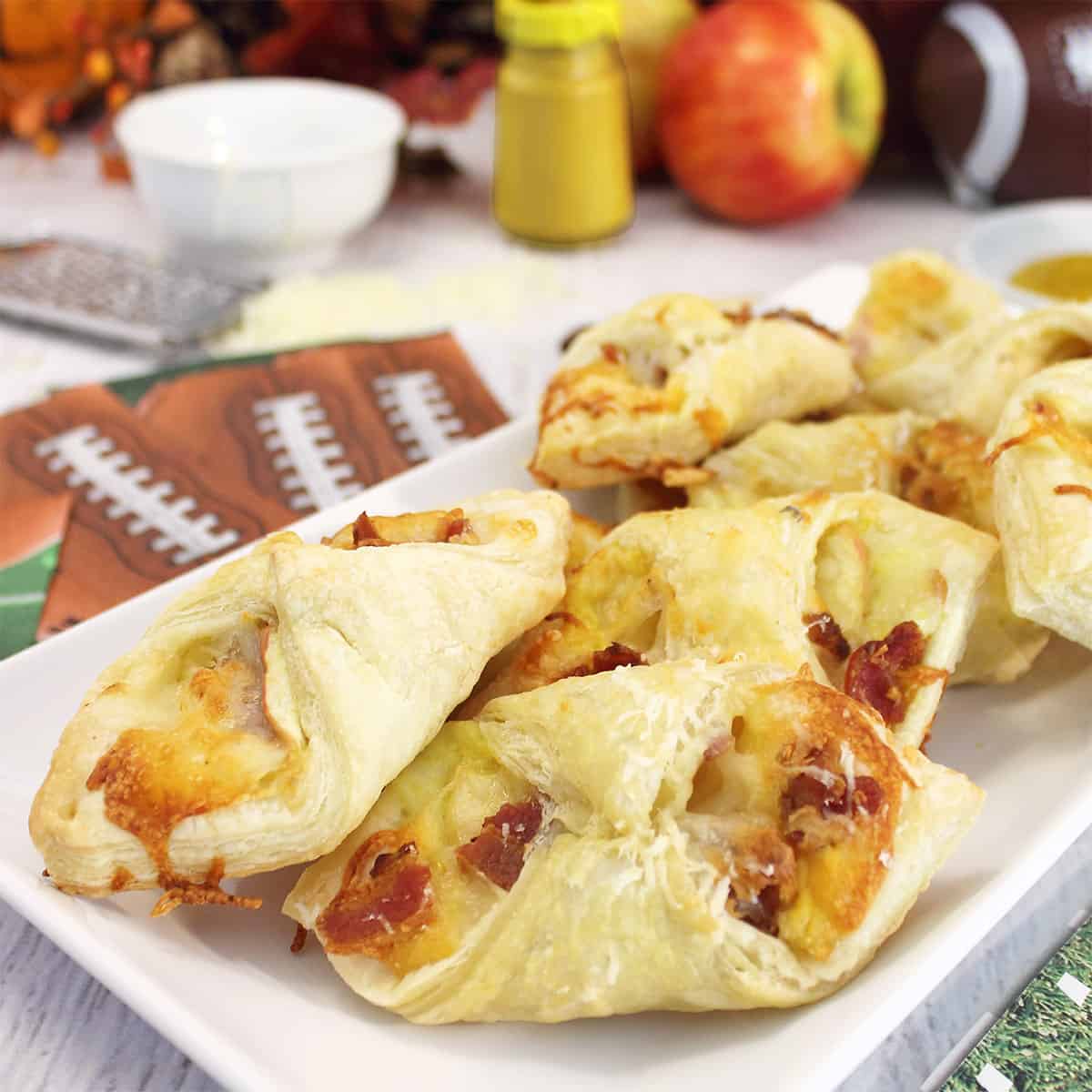 Plated cheesy apple bacon bundles with apple and mustard in back.