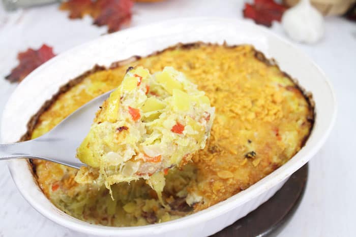 A spoonful of yellow squash casserole in white bowl.