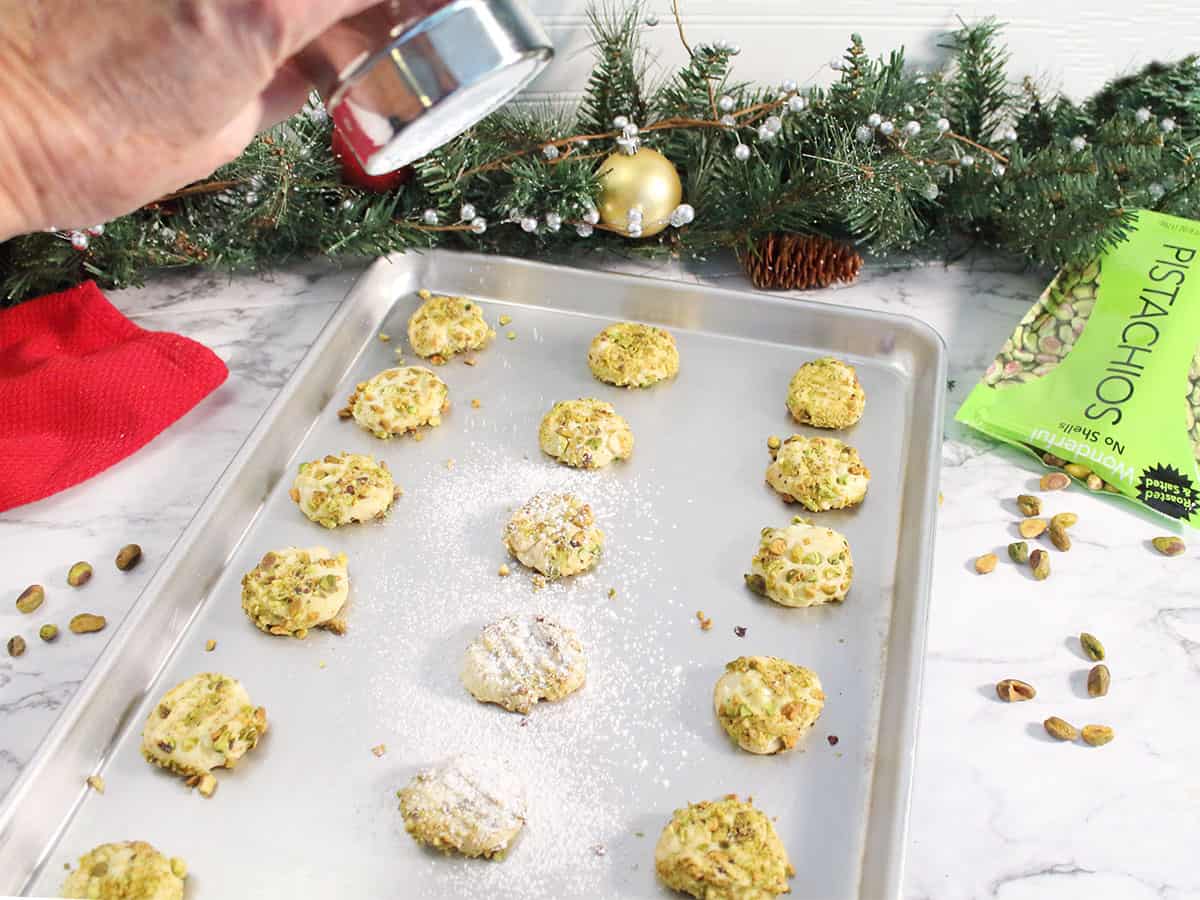 Dusting baked cookies with powdered sugar.