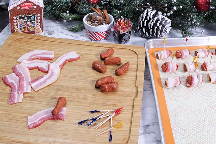 Ingredients laid out on cutting board with some smokies wrapped on cookie sheet.