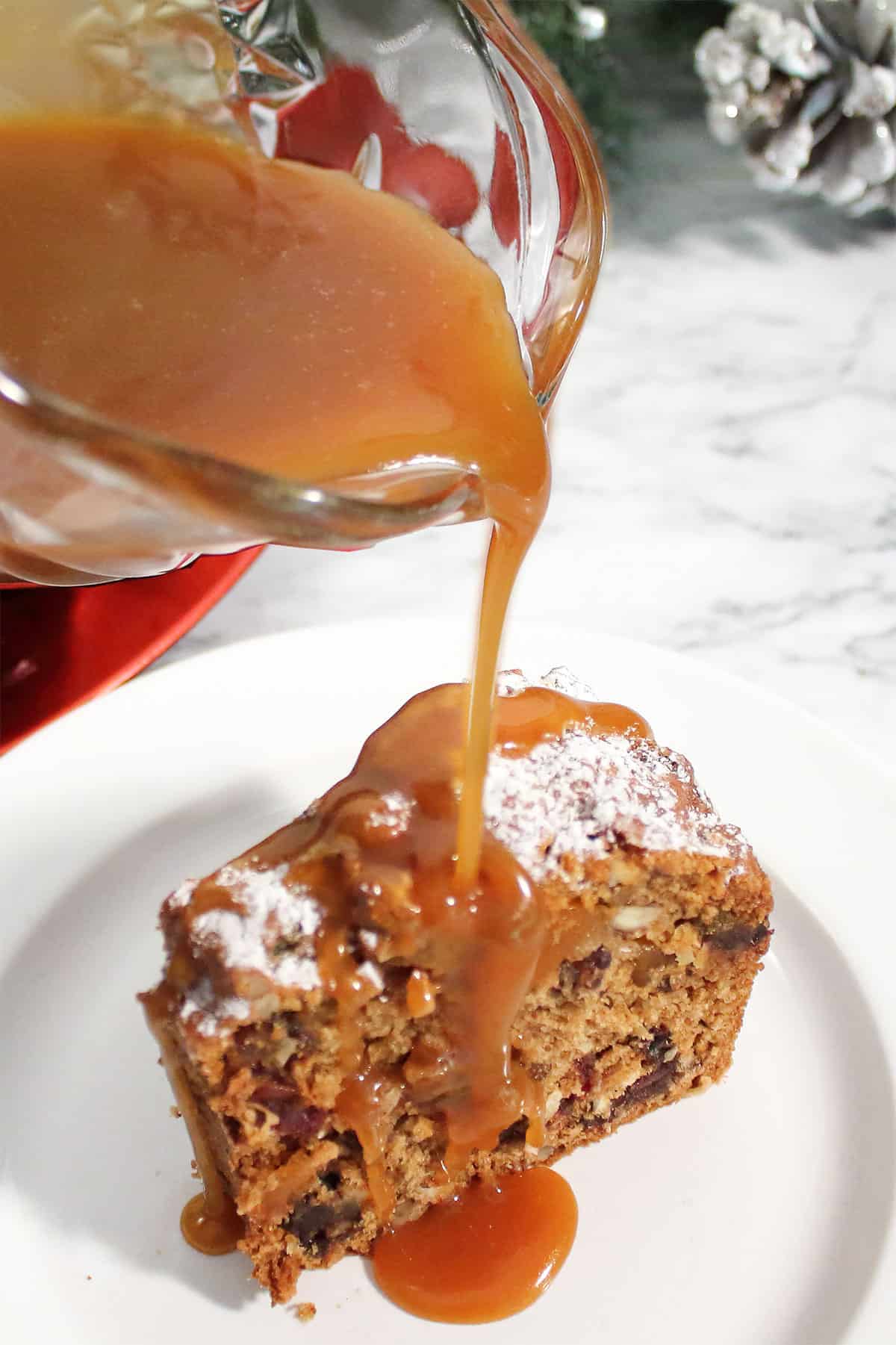 Drizzling caramel sauce over fruit cake slice.