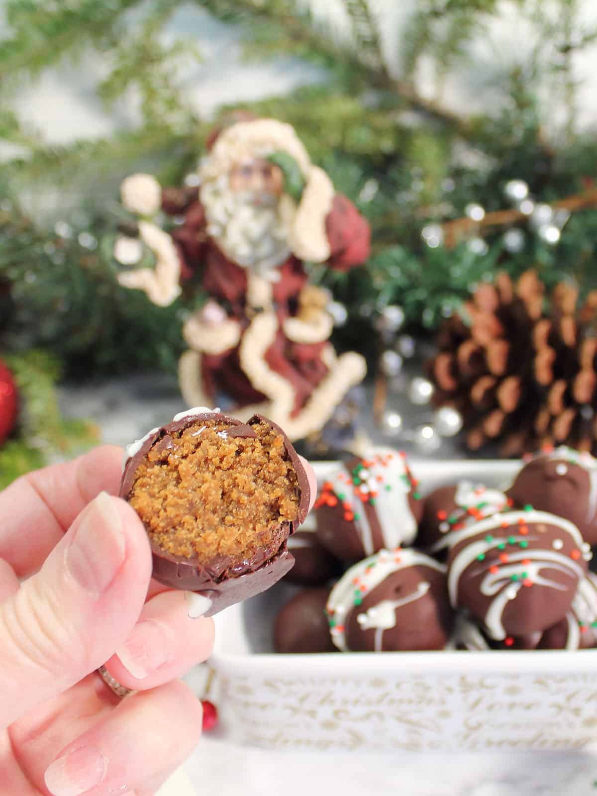 Holding a gingerbread truffle with a bite out of it.