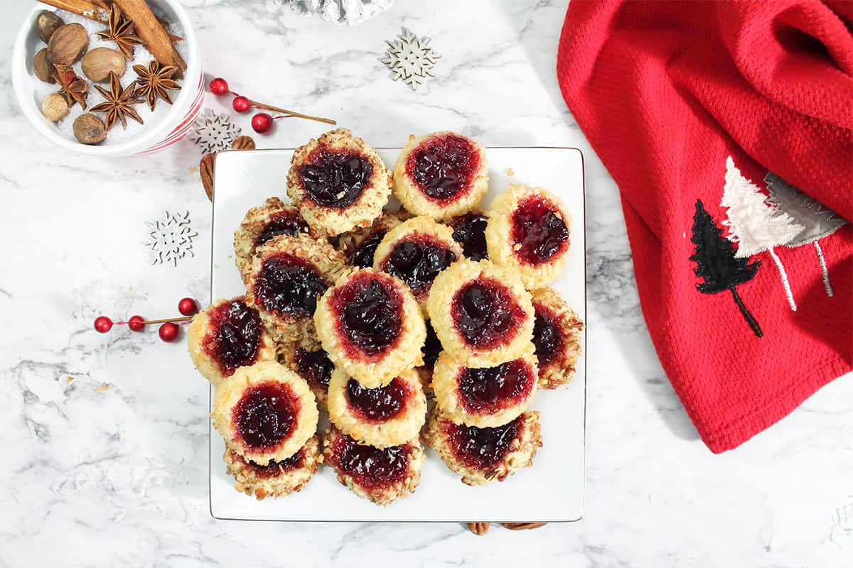Overhead of plate of shrobread thumbprint cookies with red Christmas tree towel.