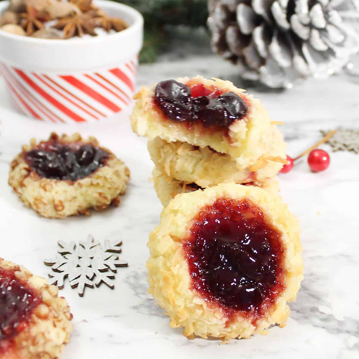 Stack of thumbprint cookies with snowflakes and pinecone.