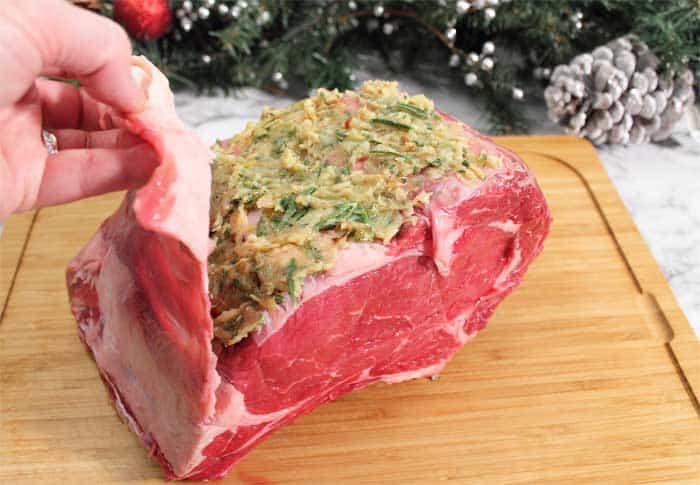 Rib Roast showing fat pulled back and garlic herb paste spread on meat.