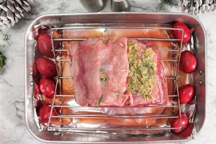 Standing Rib Roast ready to bake with potatoes around it.