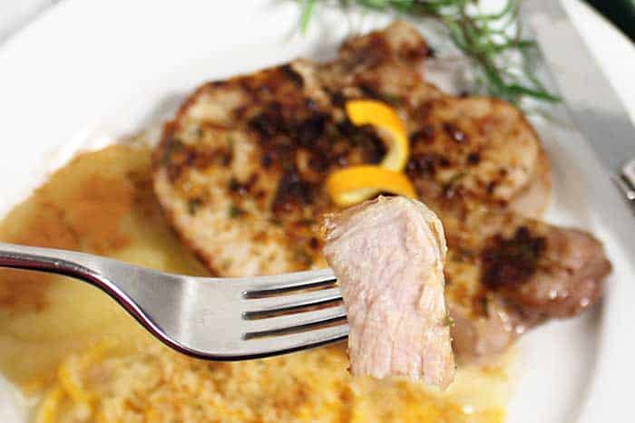 Bite of pork chop over dinner plate.