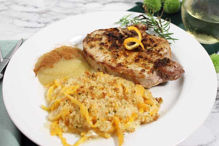 Pork Chop dinner plated with applesauce and butternut squash mac and cheese.