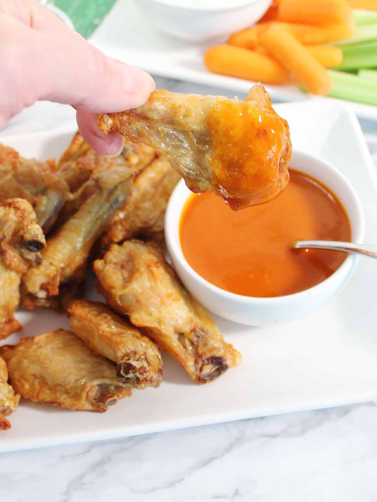 Dipping wing into buffalo sauce.