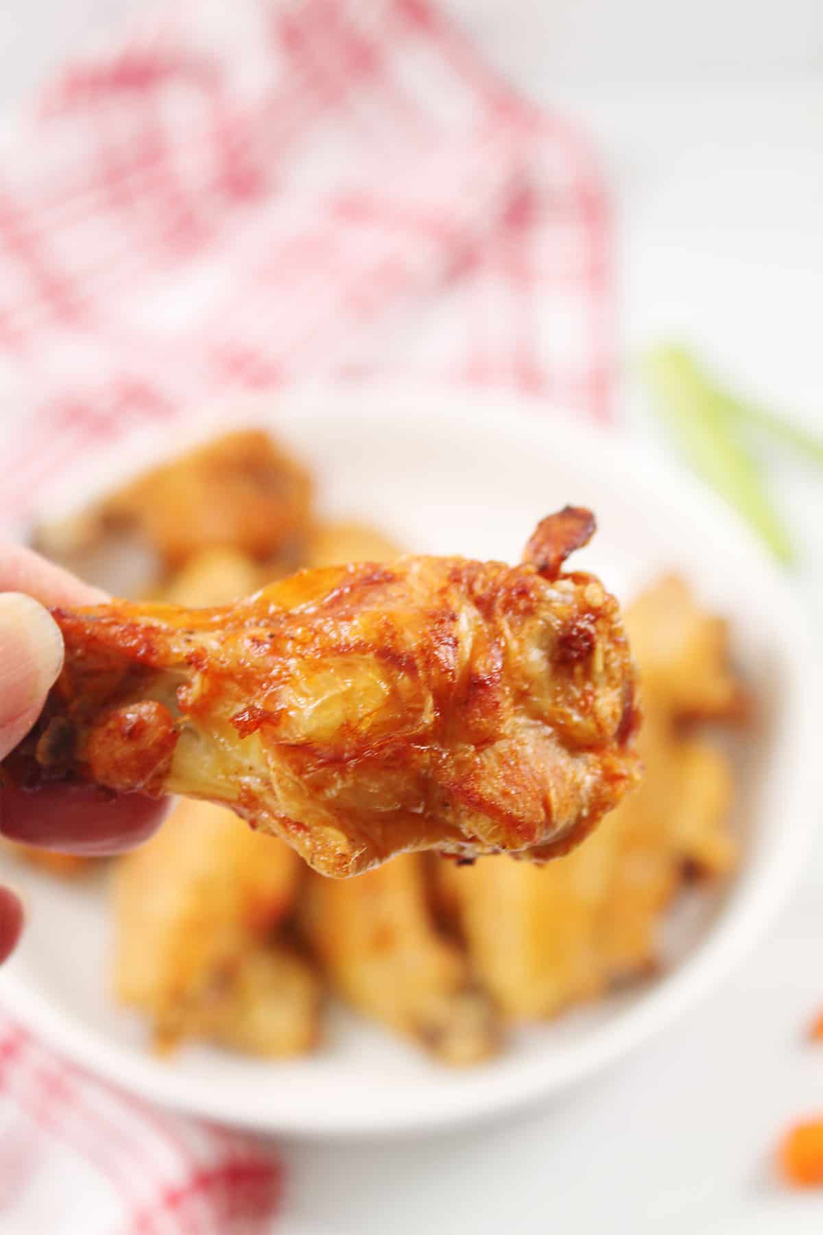 Holding air fried chicken wing over serving bowl.