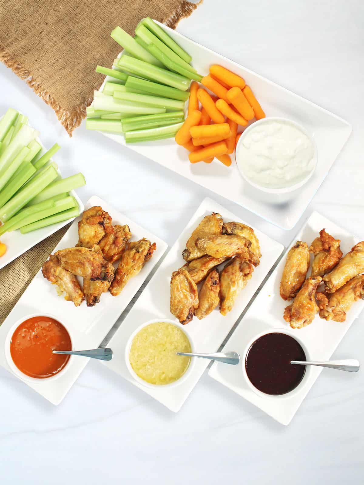 Three platters of chicken wings with wing sauce.