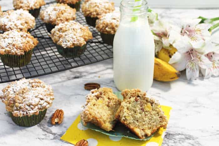 Cut muffin beside jug of milk with remaining muffins on wire rack in background.