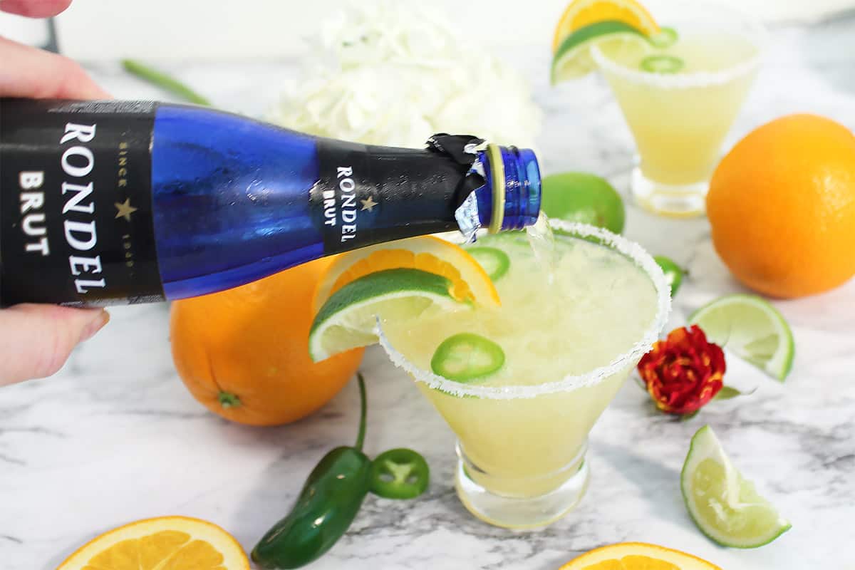 Pouring prosecco into margarita mixture.