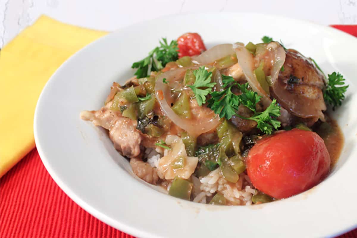 Serving of cacciatore in white bowl on red placemat with yellow napkin.