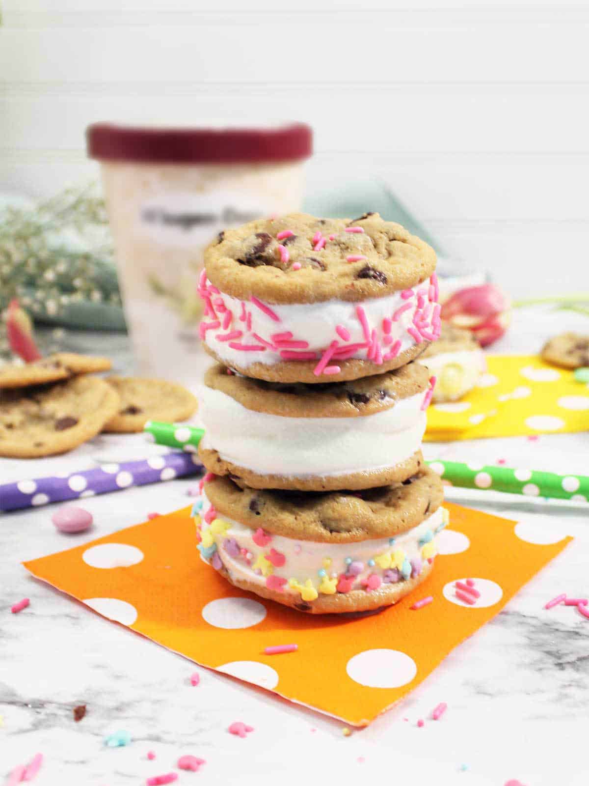 Stacked ice cream sandwiches with ice cream in background.