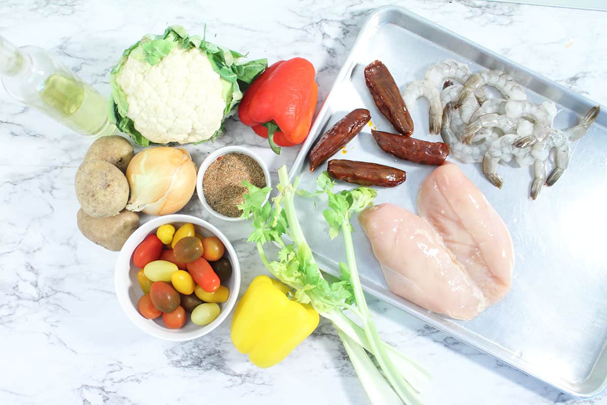 Ingredients for Creole Chicken and Shrimp Sheet Pan Dinner laid out on white table.