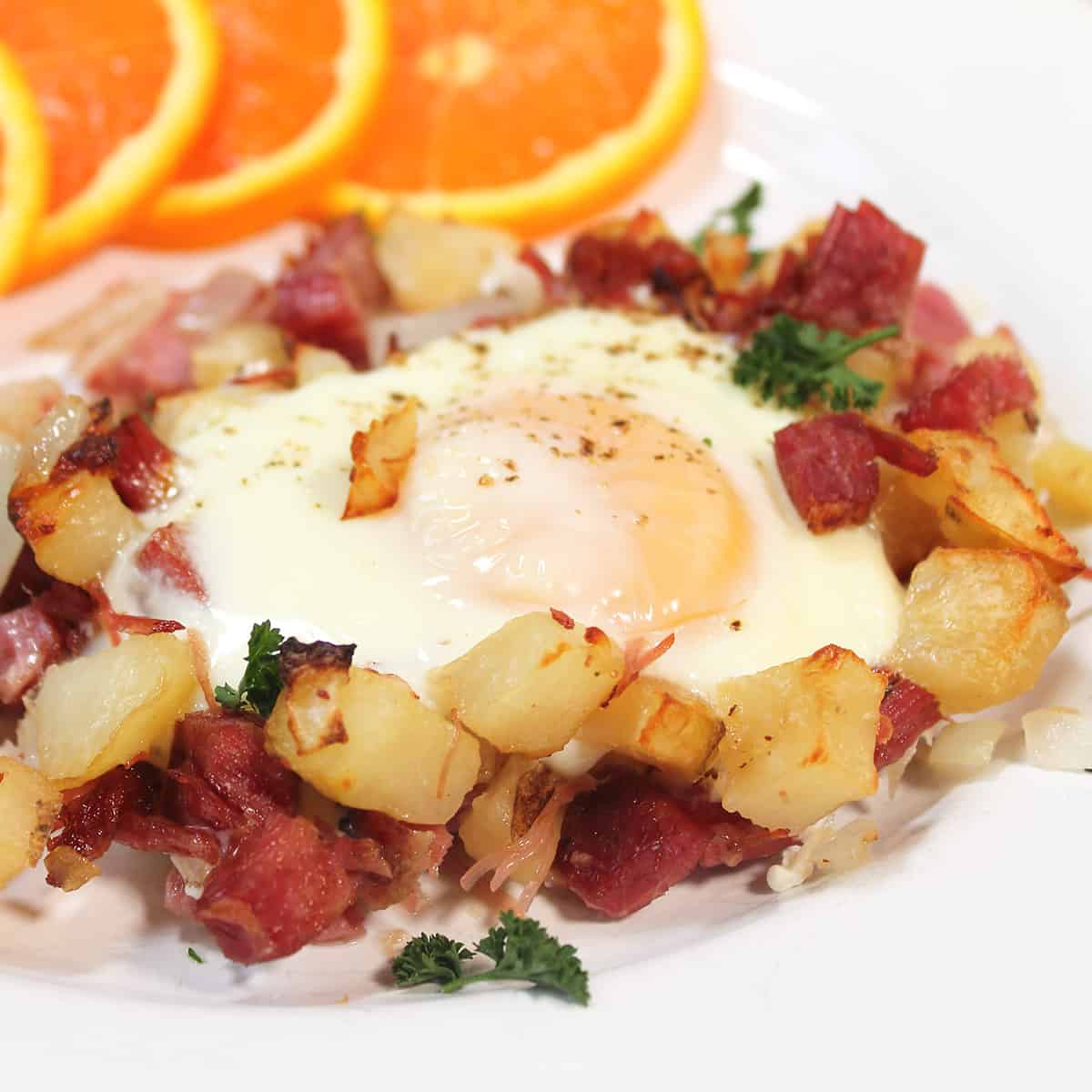 Plated corned beef hash breakfast with orange slices.