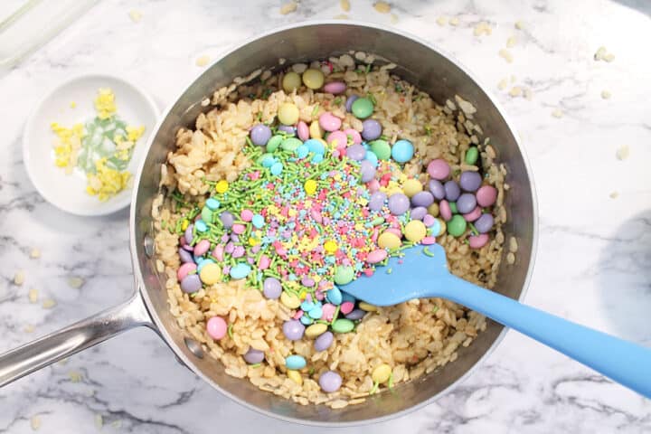 Adding in pastel m&ms candy and sprinkles to the bowl.