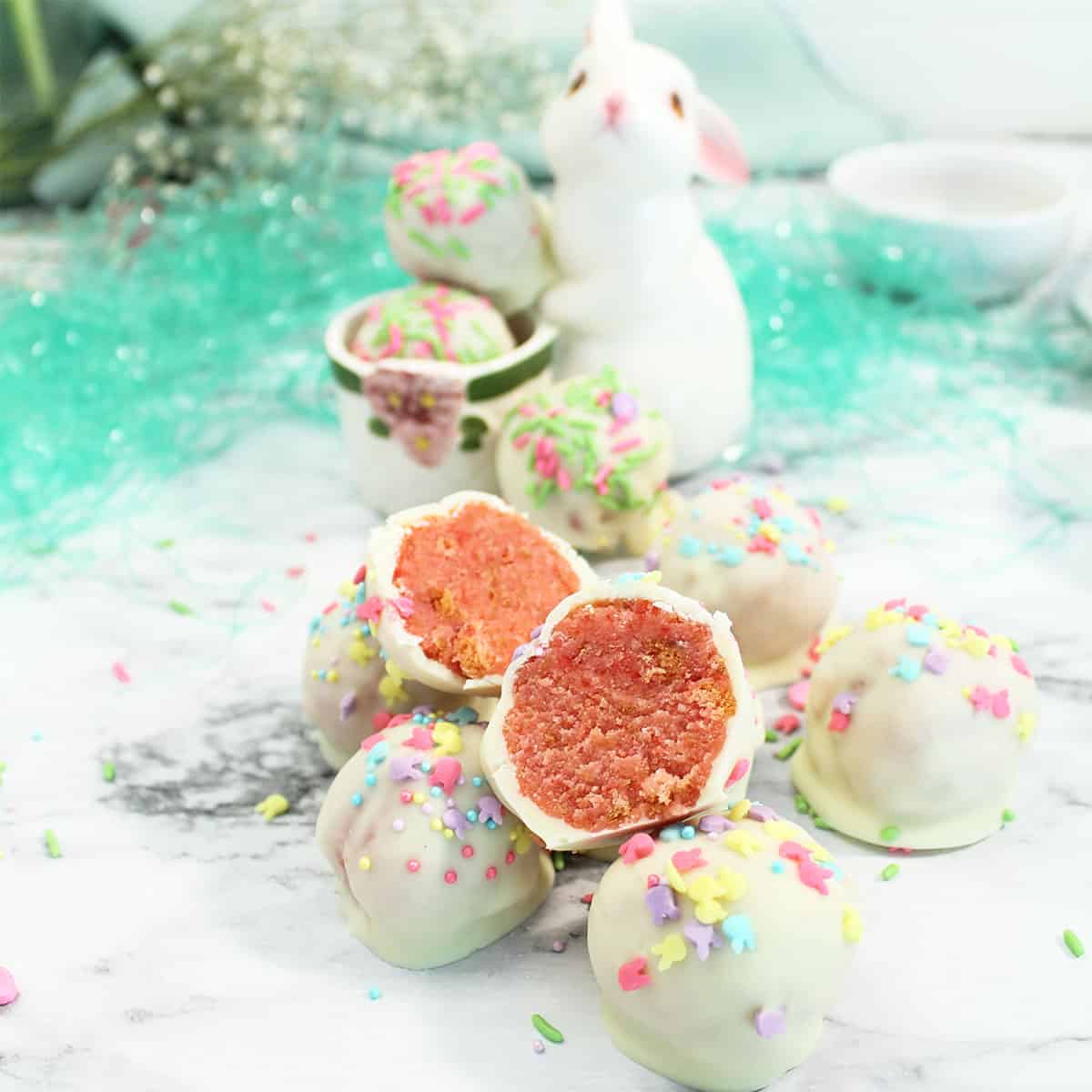 Bunny holding cake balls with a halved one in front.