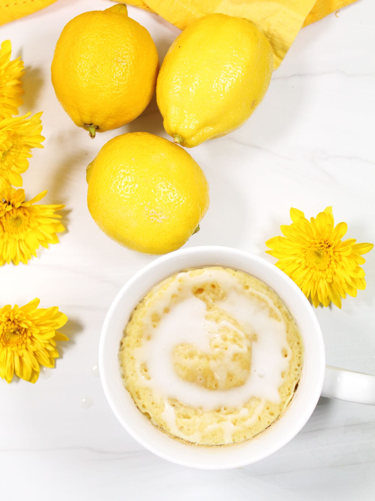 Overhead of lemon cake in a mug with lemon glaze.