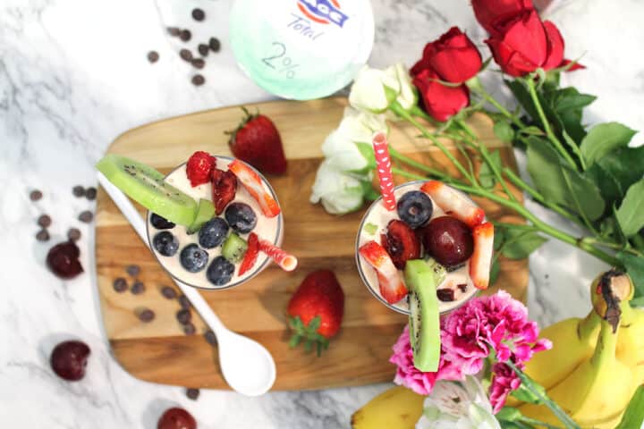 Overhead of cherry vanilla smoothies on wooden board with fruit garnish.
